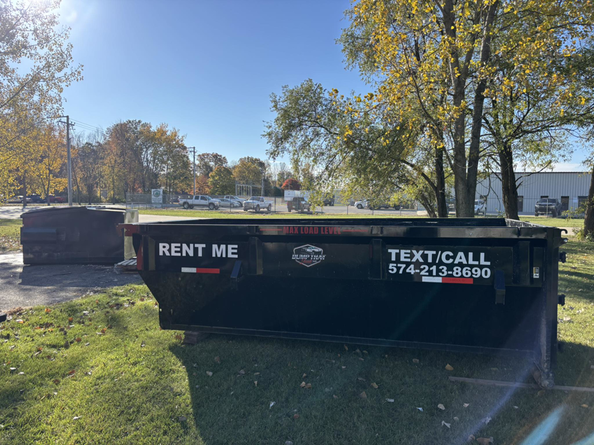 A Dump that Junk LLC dumpster placed on a grassy area near a commercial setting in Mishawaka, IN.