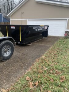 A Bluff City Dumpsters roll-off dumpster placed on a residential driveway next to a garage in Memphis, TN.