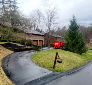 A red dumpster from Affordable Dumpsters positioned on a sloped residential driveway in Watervliet, NY.