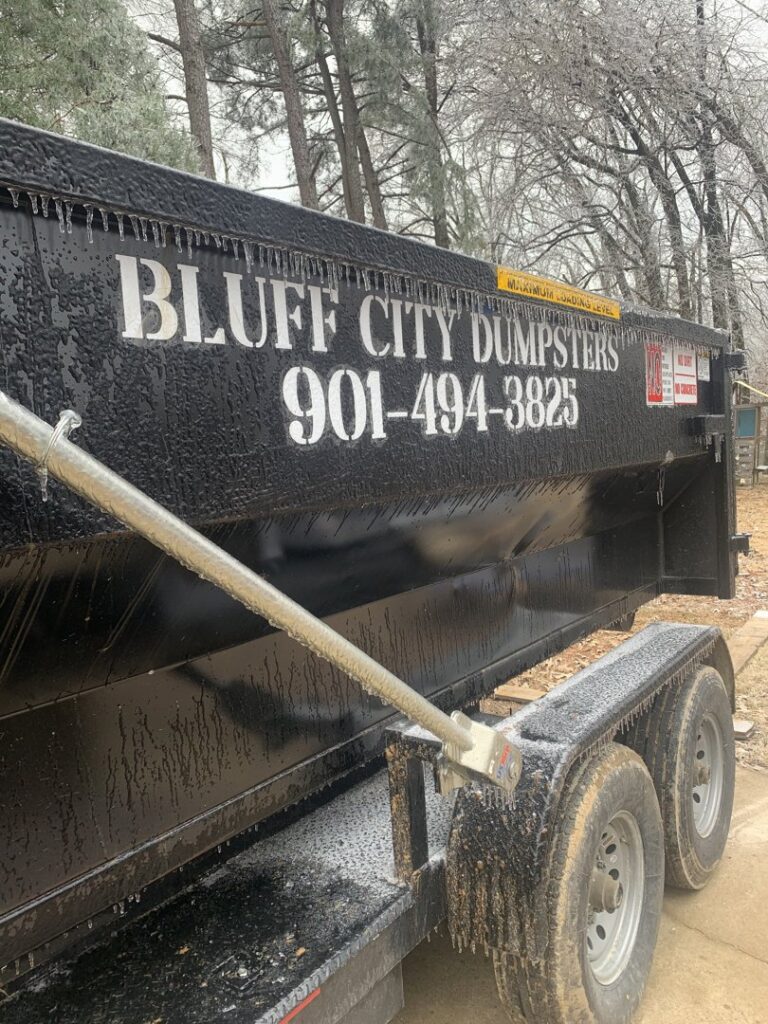 A Bluff City Dumpsters roll-off dumpster on a trailer next to another storage container in Memphis, TN.