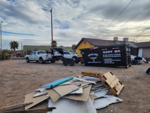 A Highland Dumpster Rentals LLC dumpster on a trailer next to a pile of construction debris in Las Cruces, NM.