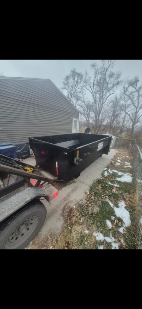 An H & H Dumpster Rental truck picking up an empty dumpster from a residential location in Rootstown, OH.
