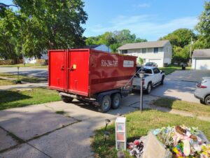 A red dumpster being picked up after a residential junk removal job by Trinity Dumpster Rental LLC in Kansas City, MO.