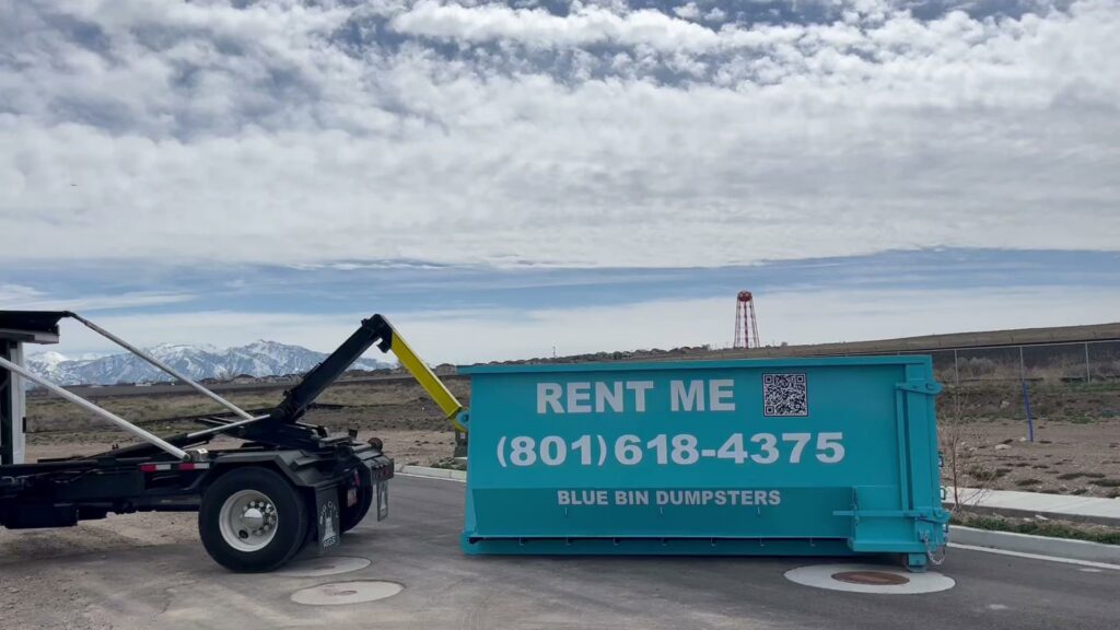 A truck preparing to pick up a blue dumpster, showcasing the junk removal service of Blue Bin Dumpster Rentals in Salt Lake City, UT.