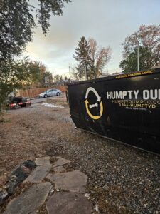 A Humpty Dump Roll-Offs & Dumpsters dumpster placed in a gravel driveway in Commerce City, CO.