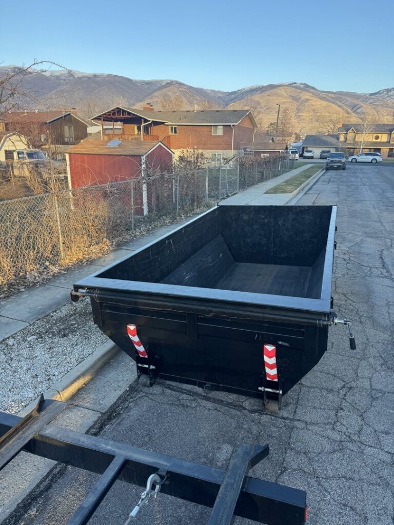 A DumpsterDash-LLC dumpster in Ogden, UT, being carefully placed on a residential street for junk removal.