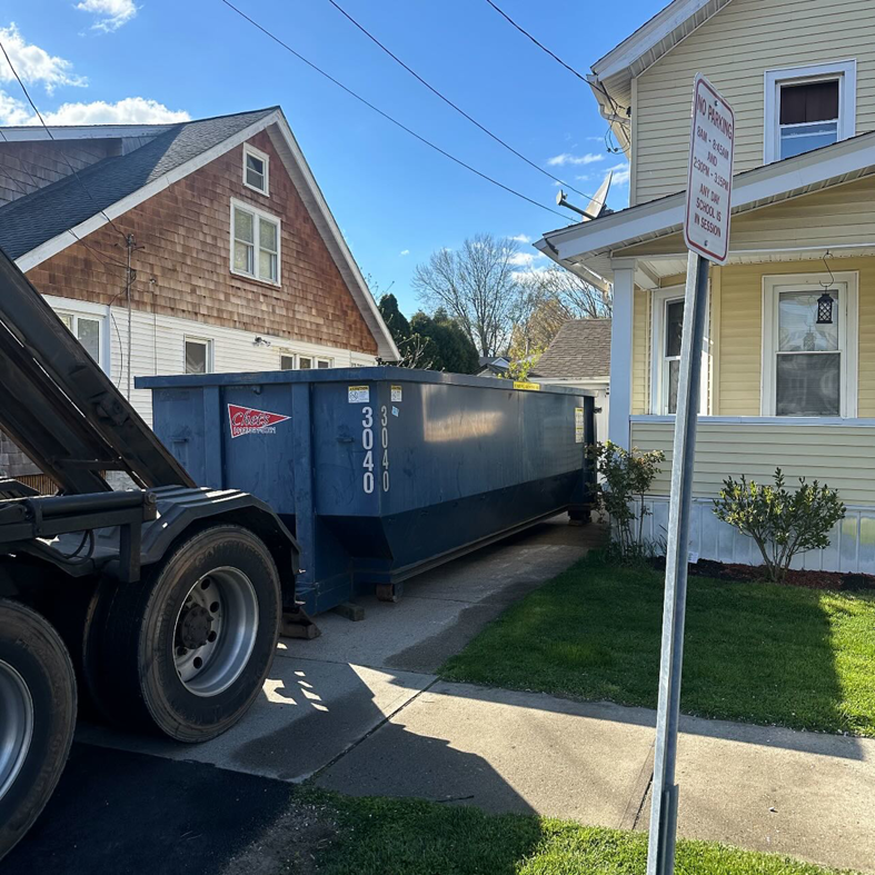 A Chet's Disposal dumpster being placed at a residential property for junk removal in Springfield, MA.