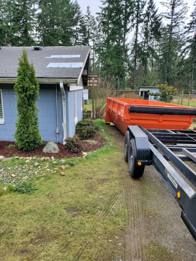 An orange roll-off dumpster being placed on a residential property by ADE Hauling in Tacoma, WA