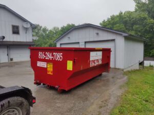A red dumpster from Trinity Dumpster Rental LLC placed in a residential setting in Kansas City, MO.