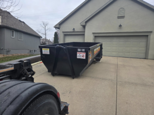 A KC TRASH GUYS LLC dumpster being placed on a residential driveway for junk removal in Johnson county, MO.