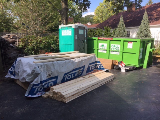 A Frog Hauling dumpster and portable toilet on a site with lumber for construction cleanup in Columbus, OH.