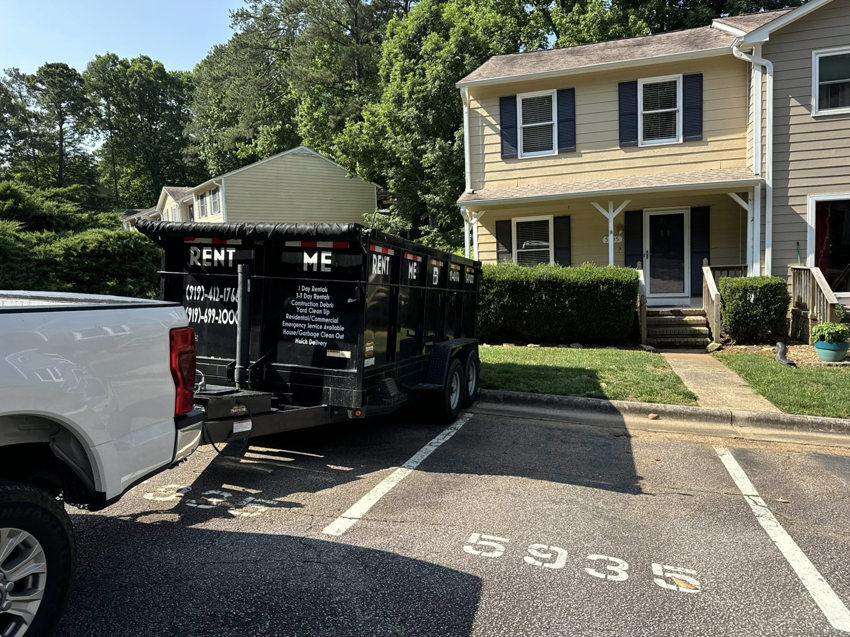 An empty dump trailer from The Dump Bros LLC parked in a residential parking lot for rental in Raleigh, NC.