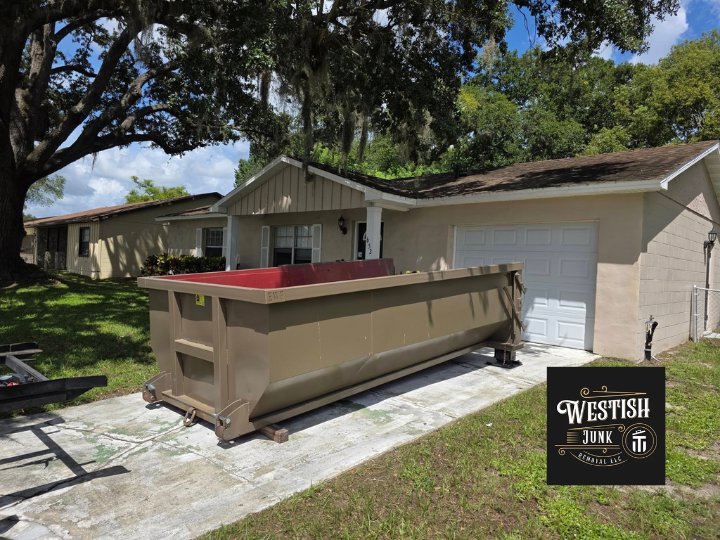 A large dumpster placed in a residential driveway for junk removal services by Westish Junk Removal LLC in Orlando, FL.