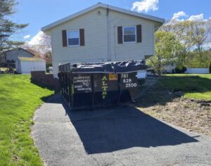 A branded dumpster from Altri Junk Removal Services parked in a residential driveway in Lynn, MA for a junk removal project.