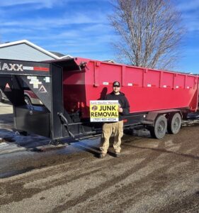 A Junk Haulin Heroes team member standing next to a large red dumpster rental trailer in Bismarck, ND.