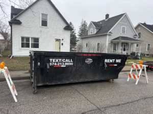 A Dump that Junk LLC dumpster rental placed on a street with traffic barriers in Mishawaka, IN.