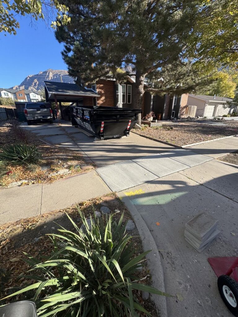 A DumpsterDash-LLC dumpster in Ogden, UT, parked in a residential driveway, ready for junk removal.