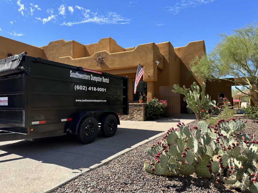 A black dumpster trailer parked in front of a residential property, ready for junk removal or debris hauling by Southwestern Dumpster Rental and Junk Removal in Peoria, AZ.