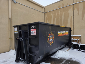 A black dumpster from KC TRASH GUYS LLC ready for junk removal service in Johnson county, MO.