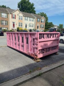 A pink dumpster from Dump It placed for junk removal in a townhouse area in Middletown, DE