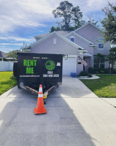 A dumpster rental trailer from Duval Dumpster Rentals, LLC in Jacksonville, FL, parked in a residential driveway for junk removal.