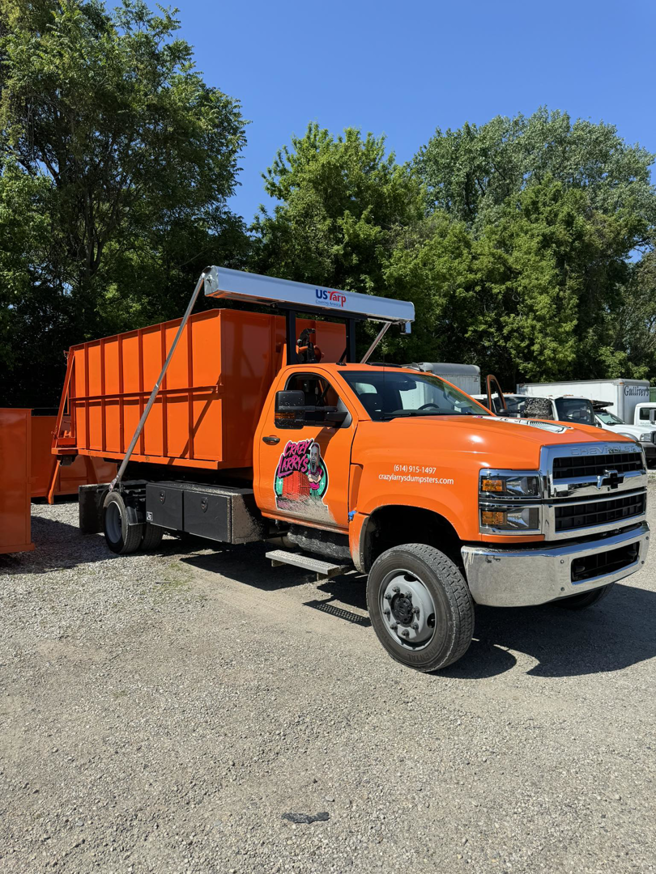 A bright orange Crazy Larry's Dumpster Rental truck with a dumpster loaded, ready for service in Columbus, OH.