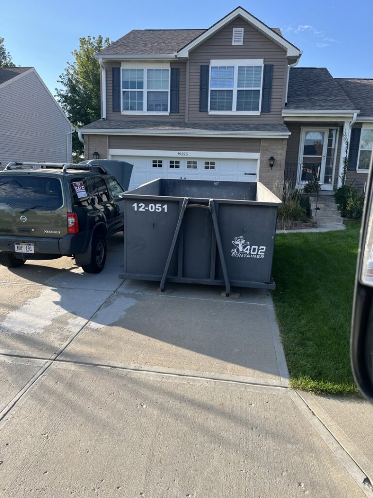 A 402 Container dumpster placed on the driveway of a residential home for junk removal in Omaha, NE.