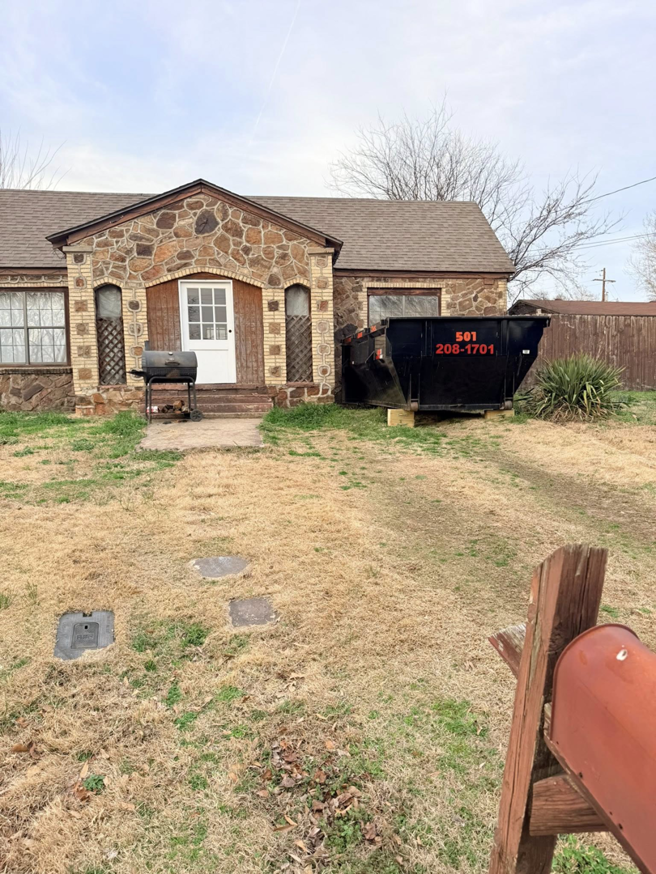 A dumpster from C&C Dumpster Rentals LLC placed in the front yard of a residential house in Conway, AR for a cleanout.