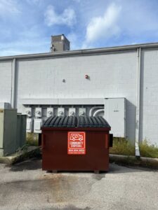A brown dumpster from Community Disposal providing waste management services next to a commercial building in Jacksonville, FL.