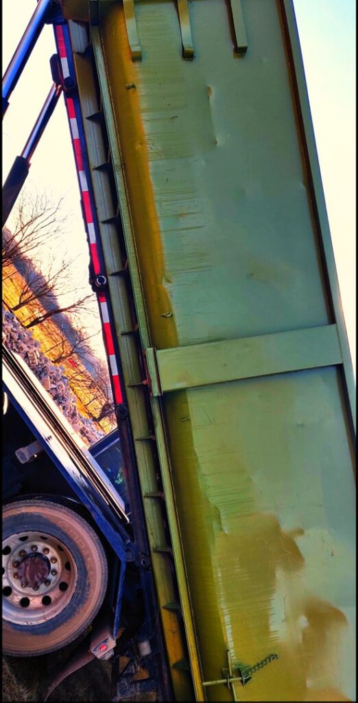 A green dumpster being tilted by a FJD Waste Disposal and Recycling LLC truck, showing the interior during a junk removal service in Dallas, TX.