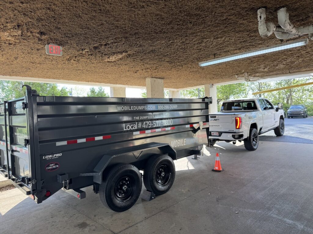 A white pickup truck delivering an empty Mobiledumps trailer for junk removal in Rogers, AR.