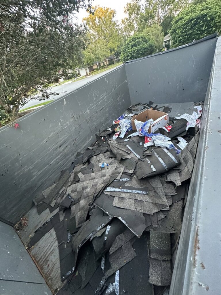 A dumpster trailer from Big Skye Dumpsters filled with old roofing shingles and debris from a junk removal job in Jacksonville, FL.