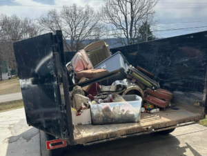 A black dump trailer filled with various household junk items and debris for Patriot Dumpster Rental in Chattanooga, TN.