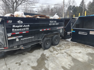 A dumpster trailer from Dumpsters RI.com - Dumpster Rentals RI filled with junk and debris, ready for removal in Rhode Island.