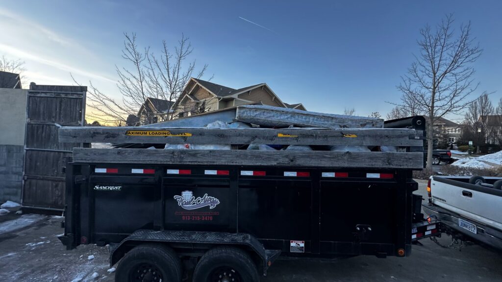 A Haul-Away Junk Removal and Dumpster Rental trailer full of construction debris parked in a driveway in Overland Park, KS.