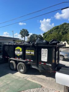A Driveway Safe Dumpster Rental trailer filled with junk and trash bags after a general junk removal job in Fort Lauderdale, FL.