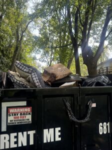 A Greybeard Dumpster Rentals trailer filled with pillows, wood, and other junk, ready for disposal in Morgantown, WV.