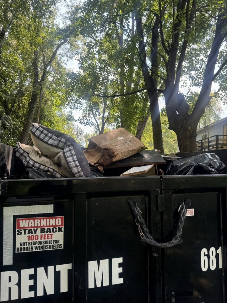 A Greybeard Dumpster Rentals trailer filled with pillows, wood, and other junk, ready for disposal in Morgantown, WV.