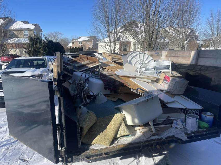 A dumpster trailer filled with various junk items, including a bathtub and construction debris, by Redline Hauling in Westerville, OH.