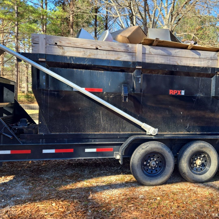 A black dumpster trailer filled with various junk and debris, ready for removal by Standard Dumpster LLC in Rock Hill, SC.