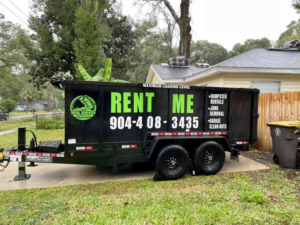 A black dumpster trailer for junk removal services from Duval Dumpster Rentals, LLC in Jacksonville, FL, parked in front of a residential home.