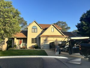 A black pickup truck positioning a dumpster trailer in a residential driveway for Waste Warriors Dumpster Rental of Des Moines, IA.