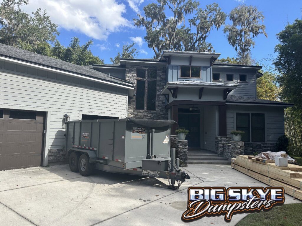 A gray dumpster trailer from Big Skye Dumpsters parked in front of a modern home in Jacksonville, FL.