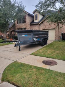 A Mobiledumps trailer parked in a residential driveway for a junk removal service in Rogers, AR.