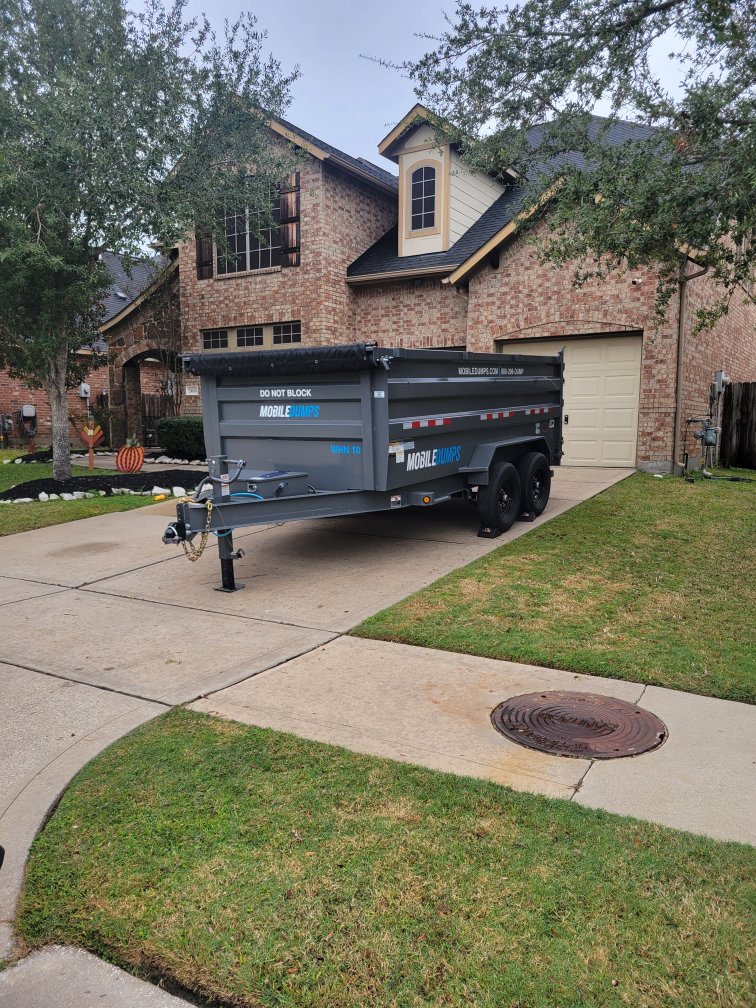 A Mobiledumps dumpster trailer parked in a residential driveway, ready for junk removal in Rogers, AR, by Mobiledumps Northwest Arkansas.