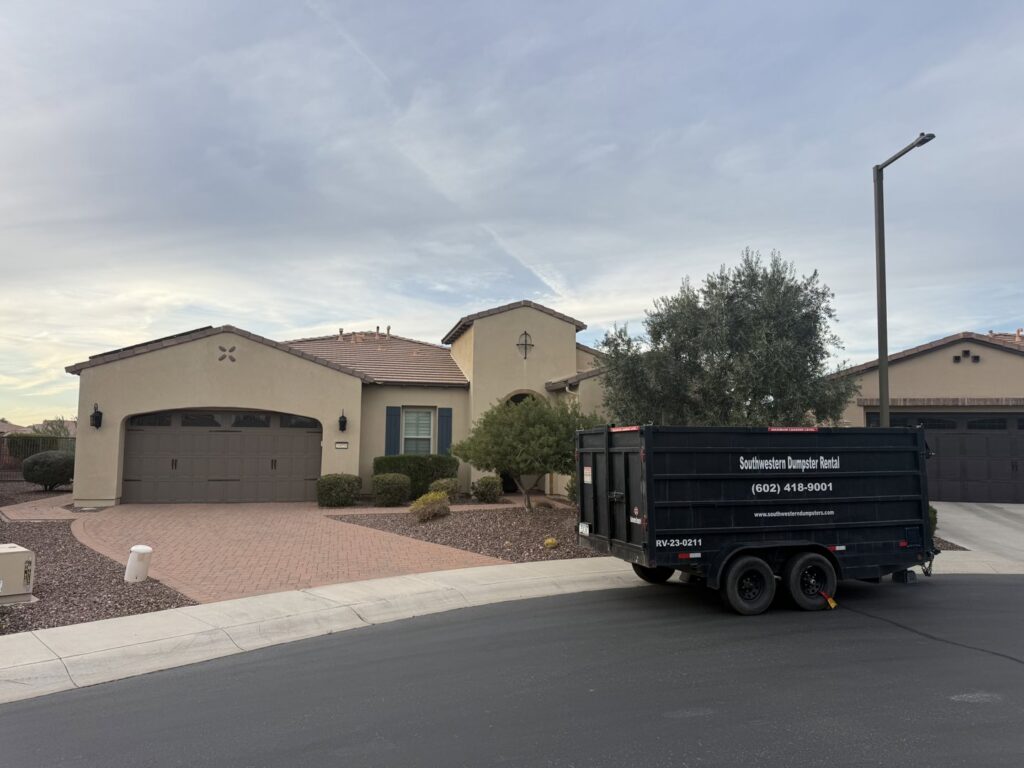 A black dumpster trailer from Southwestern Dumpster Rental and Junk Removal parked on a residential street in Peoria, AZ, ready for a junk removal project.
