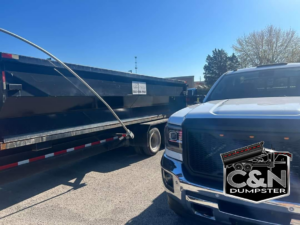 A white pickup truck with C&N Dumpster logo hitched to a black dumpster trailer in Louisville, KY