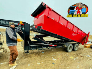A Junk Haulin Heroes team member next to a large red dump trailer being unloaded at a site in Bismarck, ND.