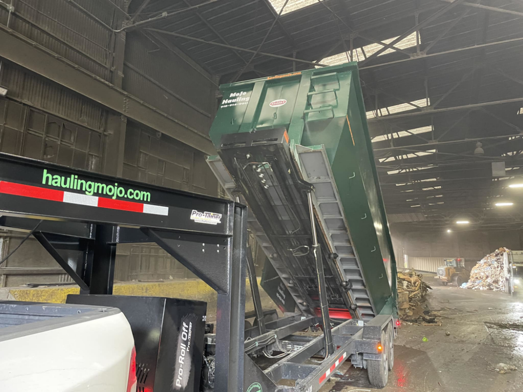 A MoJo Hauling LLC dumpster trailer actively unloading junk at a disposal facility in Bartlesville, OK.