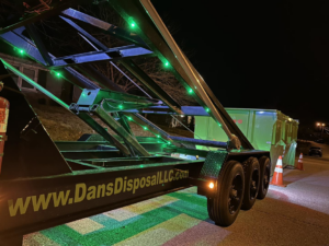 A Dan's Disposal LLC dumpster trailer with green lights at night, ready for service in Richmond, KY.